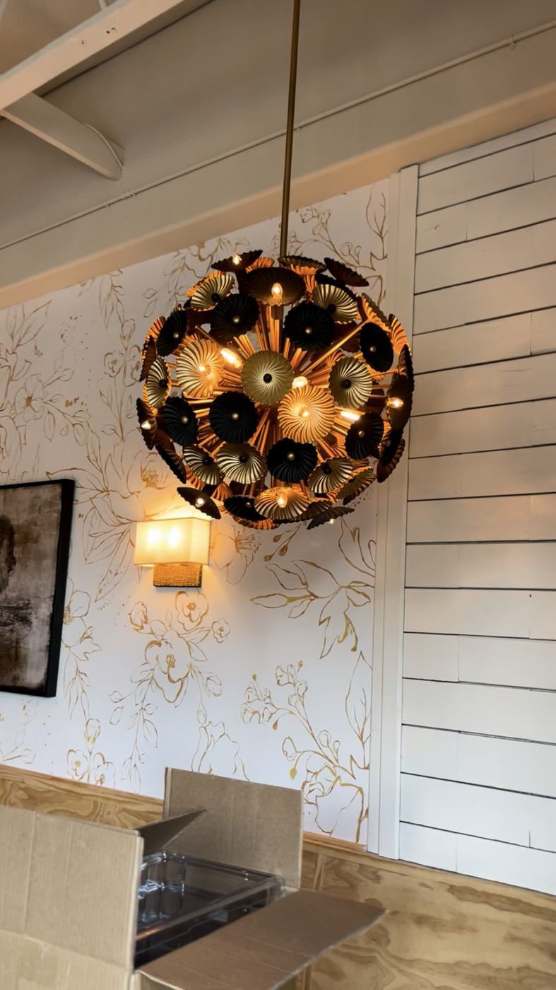Gold floral pendant light against wallpaper + shiplap feature wall