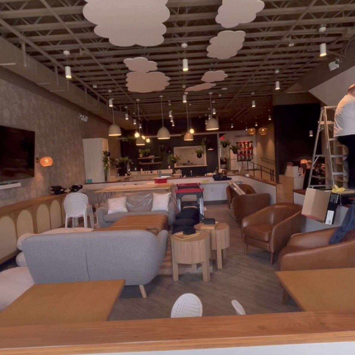 Lounge/cafe TI with acoustic cloud ceiling and pendant lighting, finish install underway