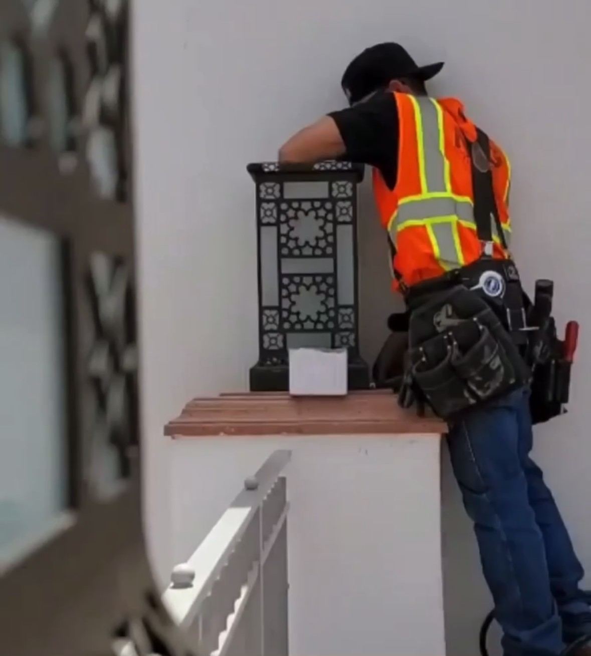 Installing a decorative metal light fixture at a stair balcony