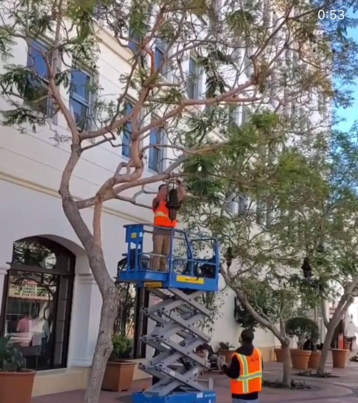 Scissor-lift work at a downtown storefront for overhead string lighting