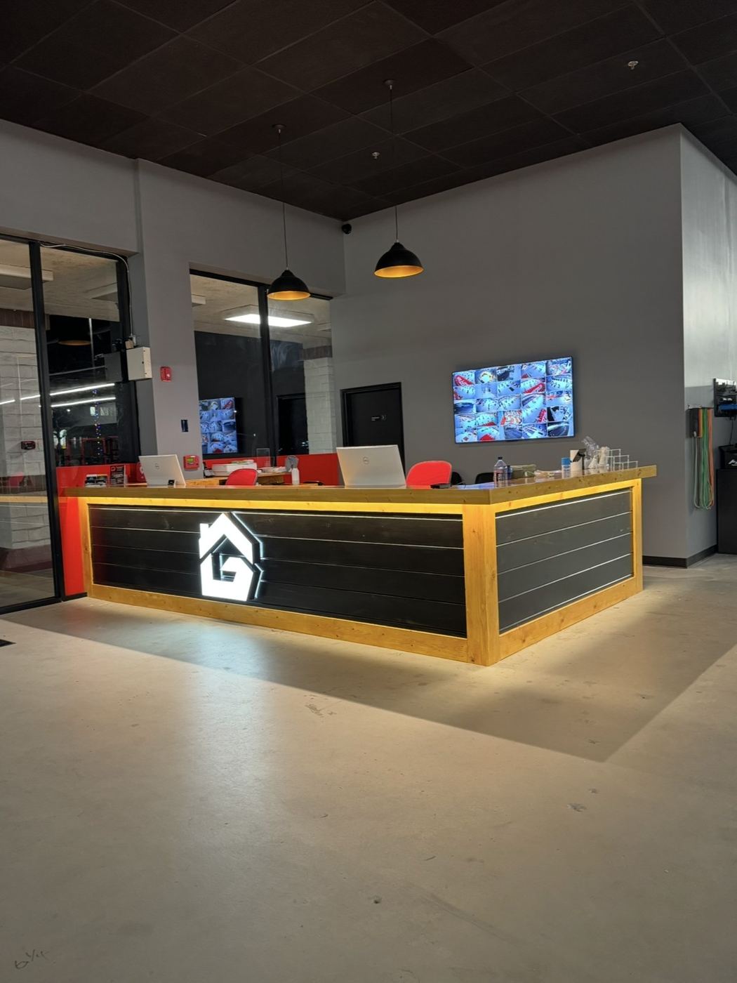Gym front desk with backlit logo wall and camera wall