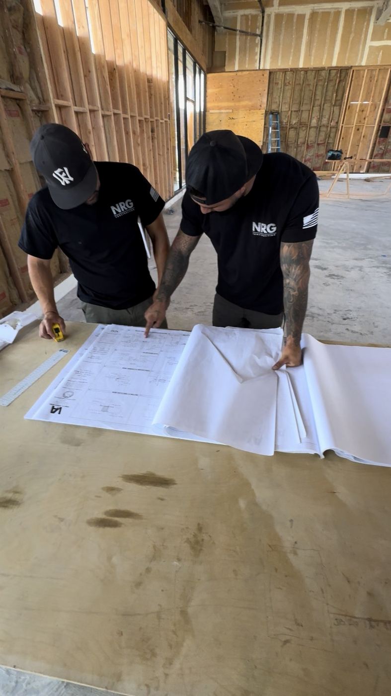 Two NRG Electric crew reviewing plans on a plywood table