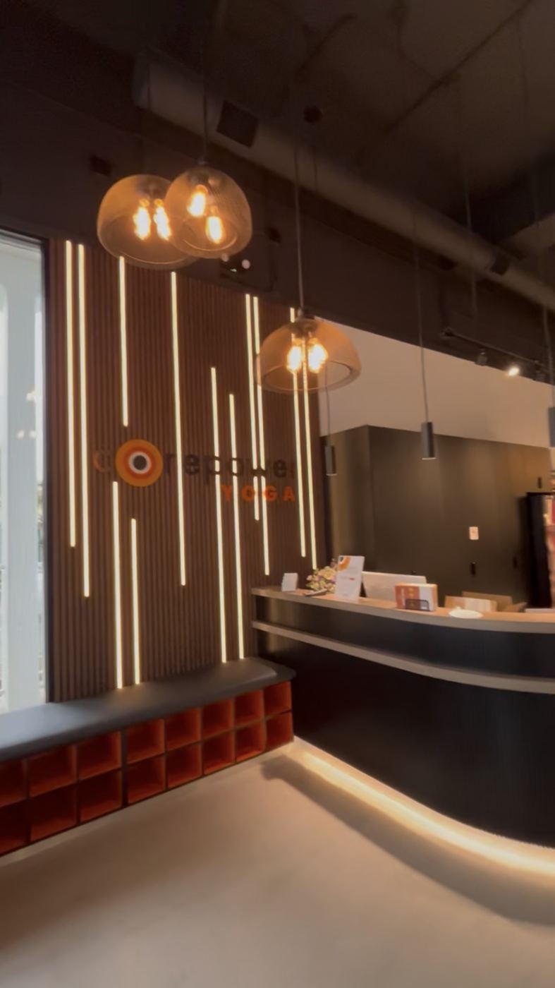 Yoga studio TI reception - backlit slat wall, pendants, curved desk
